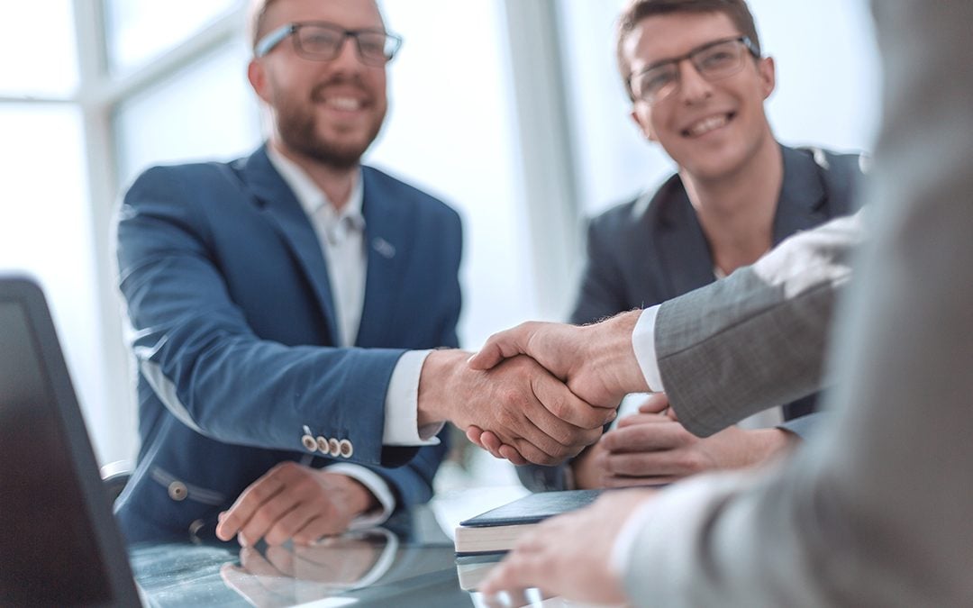 Three men at business bank smiling and shaking hands